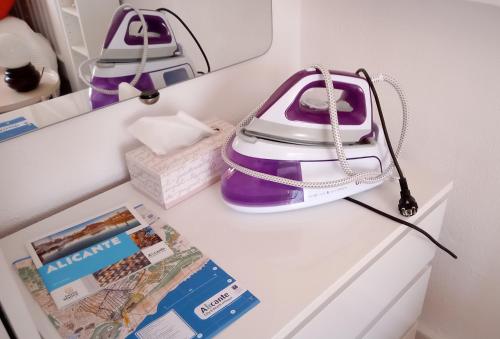 un bolso púrpura y blanco sentado en la parte superior de un refrigerador en Habitación con baño privado en piso familiar, en Alicante