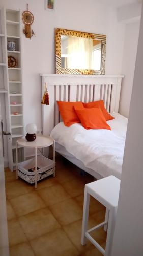 1 dormitorio con 1 cama con almohadas de color naranja y espejo en Habitación con baño privado en piso familiar, en Alicante