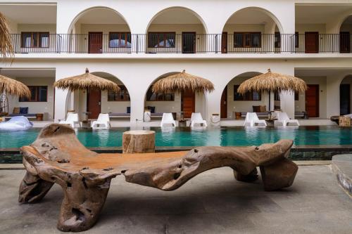 a wooden bench in front of a swimming pool at El Tropico Boutique Hotel in Kuta Lombok