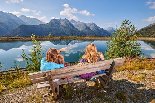 two women sitting on a bench looking at a lake at Hotel Garni Central - Zimmer - Studios - Apartments in Kappl