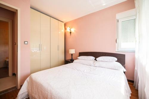- une chambre avec un lit blanc et un mur rose dans l'établissement House Antonia by the sea AE1556, à Sukošan