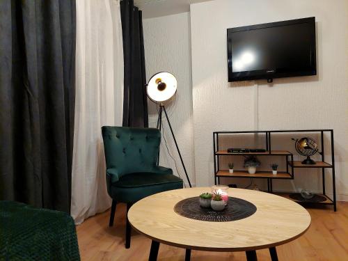 a living room with a table and a chair and a television at Apartman Uno in Osijek