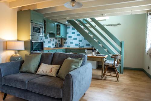 a living room with a couch and a kitchen at Brosterfield Cottage in Foolow