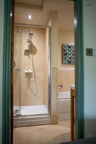 a bathroom with a shower with a glass door at Brosterfield Cottage in Foolow