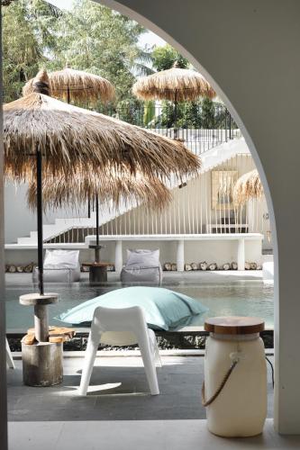 a patio with a table and a chair and umbrella at El Tropico Boutique Hotel in Kuta Lombok