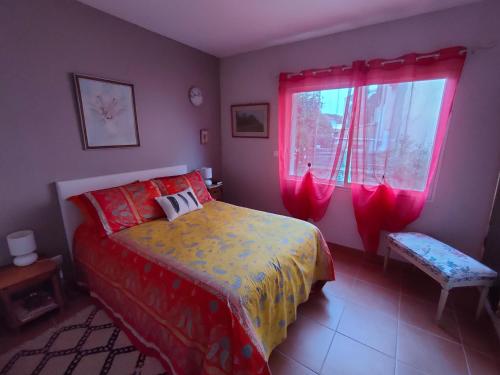 Schlafzimmer mit einem Bett und einem Fenster mit roten Vorhängen in der Unterkunft Chez Régine in Agde