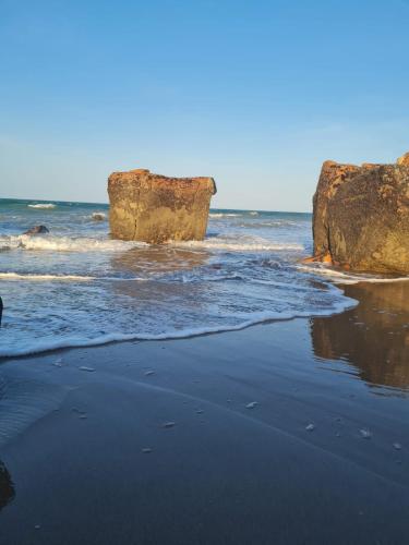 a beach with two large rocks in the ocean at Casa da Peroba Sol - Pé na Areia - Praia da Peroba - Icapuí in Icapuí