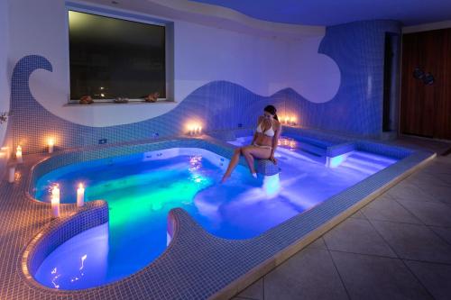 a woman sitting in a swimming pool at night at Nero D'Avorio Aparthotel & SPA in Rimini