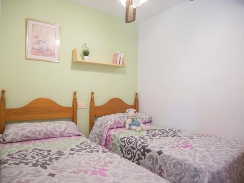 two beds in a bedroom with a teddy bear sitting on them at Apartamentos Sol Y Mar in Alcossebre