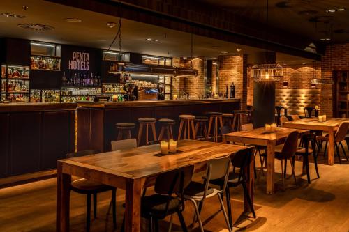 a restaurant with wooden tables and a bar at Pentahotel Rostock in Rostock
