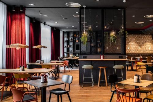 a restaurant with tables and chairs and red curtains at Pentahotel Rostock in Rostock