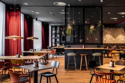 ein Restaurant mit Tischen, Stühlen und roten Vorhängen in der Unterkunft Pentahotel Rostock in Rostock