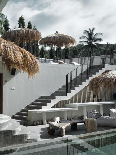 a resort with stairs and a pool with a bench at El Tropico Boutique Hotel in Kuta Lombok