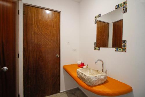 La salle de bains est pourvue d'un lavabo orange et d'une porte en bois. dans l'établissement Coco Resort & Villas, 