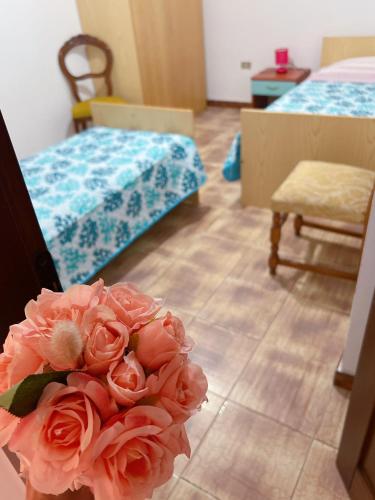 une chambre avec deux lits et un vase de roses roses dans l'établissement CASA VACANZE DA RITA., à Stintino