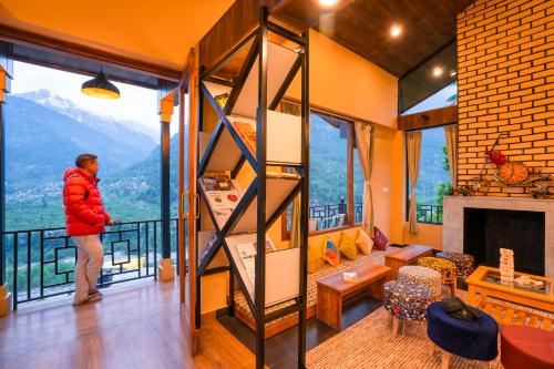 a man is standing in a room with a balcony at Zostel Manali, Vashisht in Vashisht