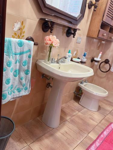 a bathroom with a sink and a vase of pink flowers at CASA VACANZE DA RITA. in Stintino