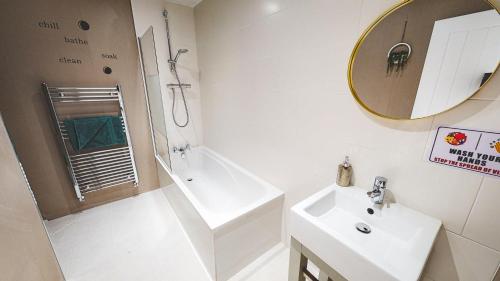 a bathroom with a sink and a tub and a mirror at Spacious 4-bed house in Crewe by 53 Degrees Property, ideal for Contractors & Business, FREE parking - sleeps 7 in Crewe