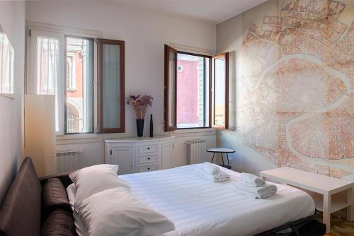 a bedroom with a bed and a table and windows at Alla Mappa, meraviglioso appartamento con vista in Venice