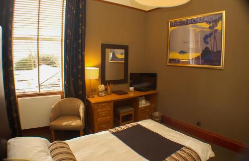 um quarto com uma cama e uma secretária com uma televisão em The Dutch Mill Hotel em Aberdeen