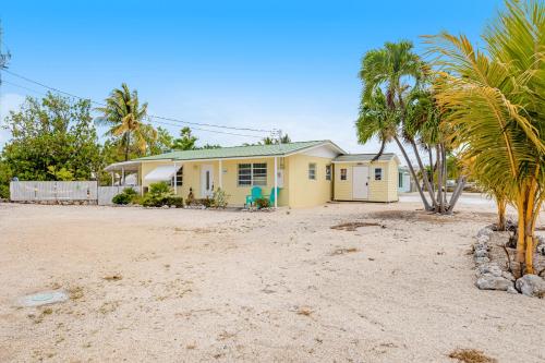 a yellow house with palm trees in front of it at Yellowtail House in Marathon