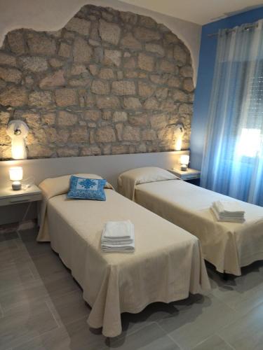 two beds in a room with a stone wall at Lungomare Bed rooms in Santa Maria Navarrese
