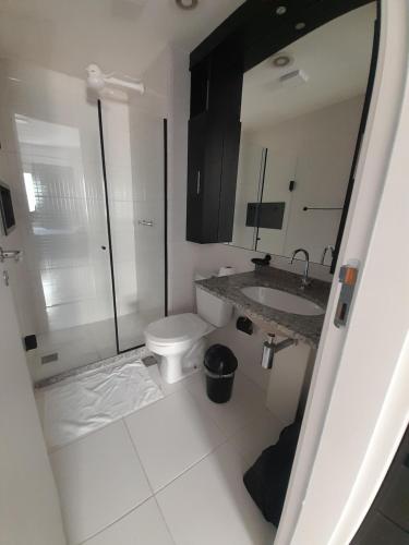 a bathroom with a toilet and a sink and a mirror at Itaguaí Flats in Itaguaí
