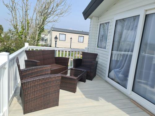 a balcony with wicker chairs and tables on a house at Mawgan Pads Perranporth in Cubert