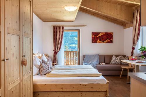 a bedroom with a bed and a couch and a window at Huberhof Appzimmer in Feldthurns