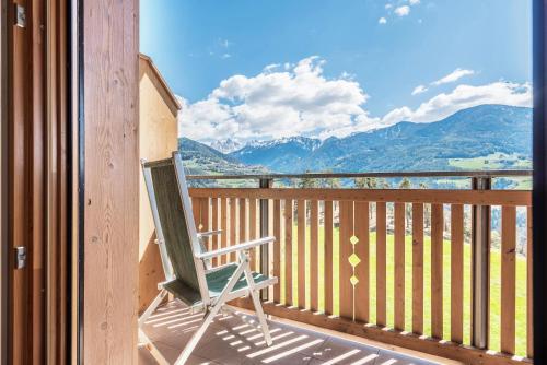 a rocking chair on a balcony with a view of mountains at Huberhof Appzimmer in Feldthurns