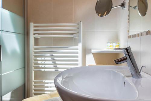 a bathroom with a white sink and a mirror at Huberhof Appzimmer in Feldthurns