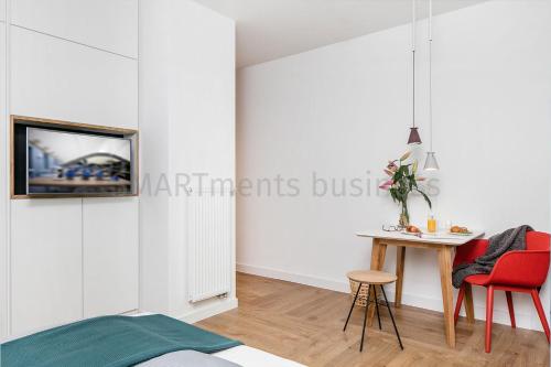 - une chambre avec des murs blancs, une table et des chaises dans l'établissement SMARTments business Berlin Prenzlauer Berg, à Berlin