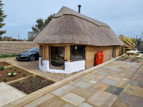 a small house with a thatched roof on a patio at The Thatchie in Deal