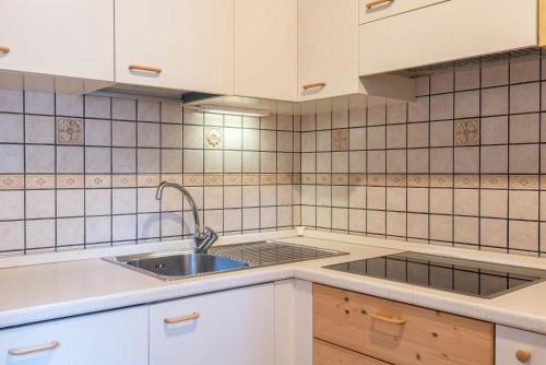 a kitchen with white cabinets and a sink at Cesa de Agnese in Canazei