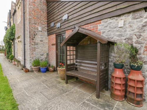 a bench sitting outside of a building with potted plants at Owls Retreat in Weston-super-Mare