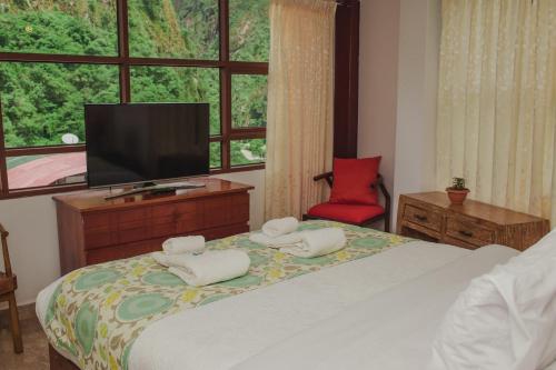 a bedroom with a bed with a television and a red chair at Rupa Rupa High Jungle Eco B&B in Machu Picchu