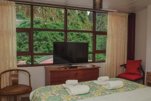 a bedroom with a bed with a television and a window at Rupa Rupa High Jungle Eco B&B in Machu Picchu