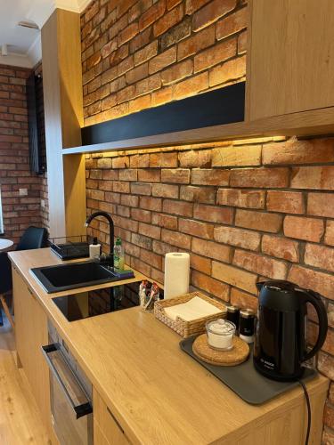 a kitchen with a counter with a brick wall at New Sobieski Apartments by OneApartments in Sopot
