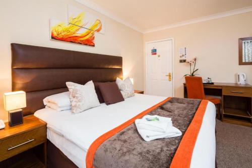 een hotelkamer met een bed, een bureau en een bureau bij Kingsland Hotel in Harrow