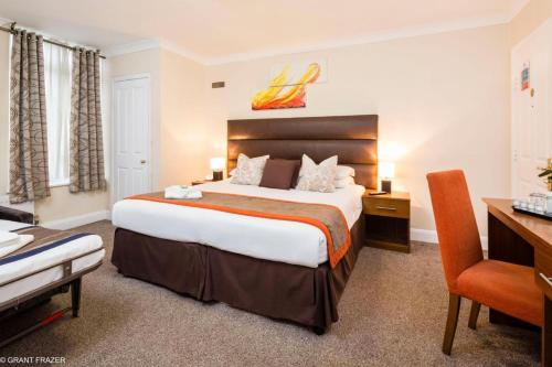 a hotel room with a large bed and a desk at Kingsland Hotel in Harrow