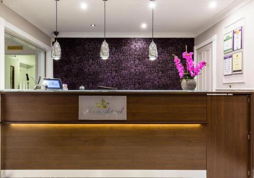 a lobby with a reception desk with purple wallpaper at Kingsland Hotel in Harrow
