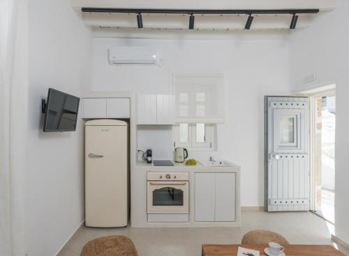 a white kitchen with a refrigerator and a tv at Karai, The House Project in Astypalaia Town
