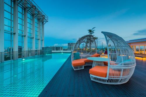 ein Swimmingpool mit Stühlen und Tischen auf einem Gebäude in der Unterkunft Suasana Suites D'Homestay01 JB Town in Johor Bahru