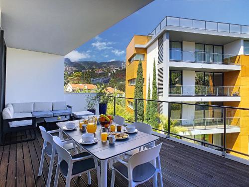 a dining table and chairs on a balcony with a building at The Bay View - by LovelyStay in Funchal