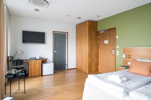 a bedroom with a bed and a desk and a television at Hiisi Hotel Helsinki Jätkäsaari in Helsinki