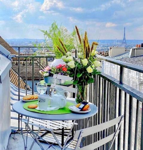 a table on a balcony with a breakfast of tea and flowers at Hotel Litteraire Marcel Ayme, BW Premier Collection in Paris