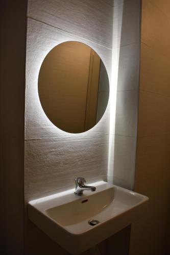 a bathroom sink with a round mirror above it at Studio2 in Katerini in Katerini