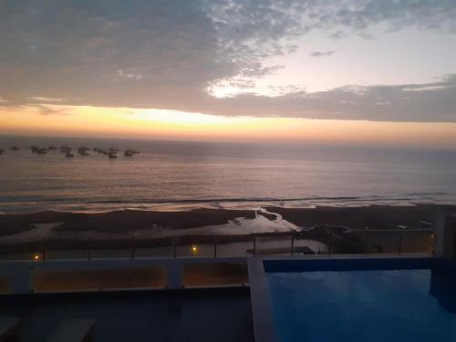 a sunset over the ocean with ships in the water at Hotel Terrazas Del Mar in Huacho