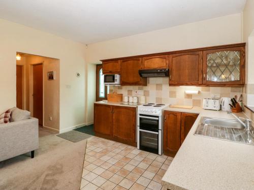 a kitchen with wooden cabinets and a stove top oven at Carthouse in Weston-super-Mare