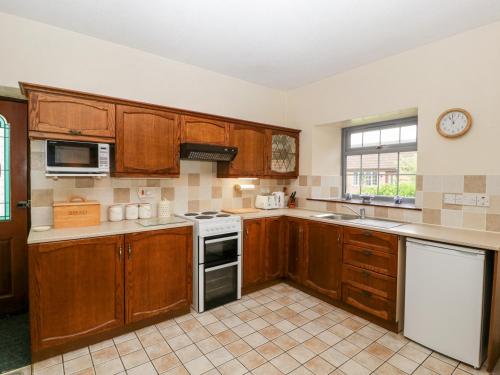 a kitchen with wooden cabinets and a stove top oven at Carthouse in Weston-super-Mare